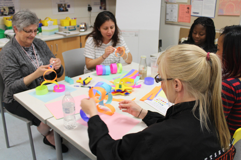 Student instructors learning methods of crafting with colored paper.